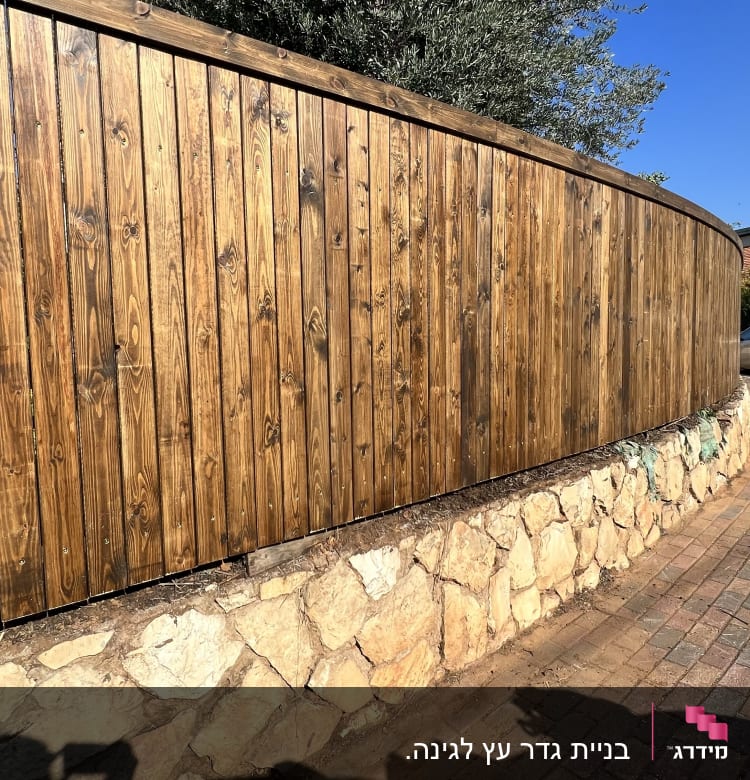 גדר עץ על קיר אבן לצד מדרכה